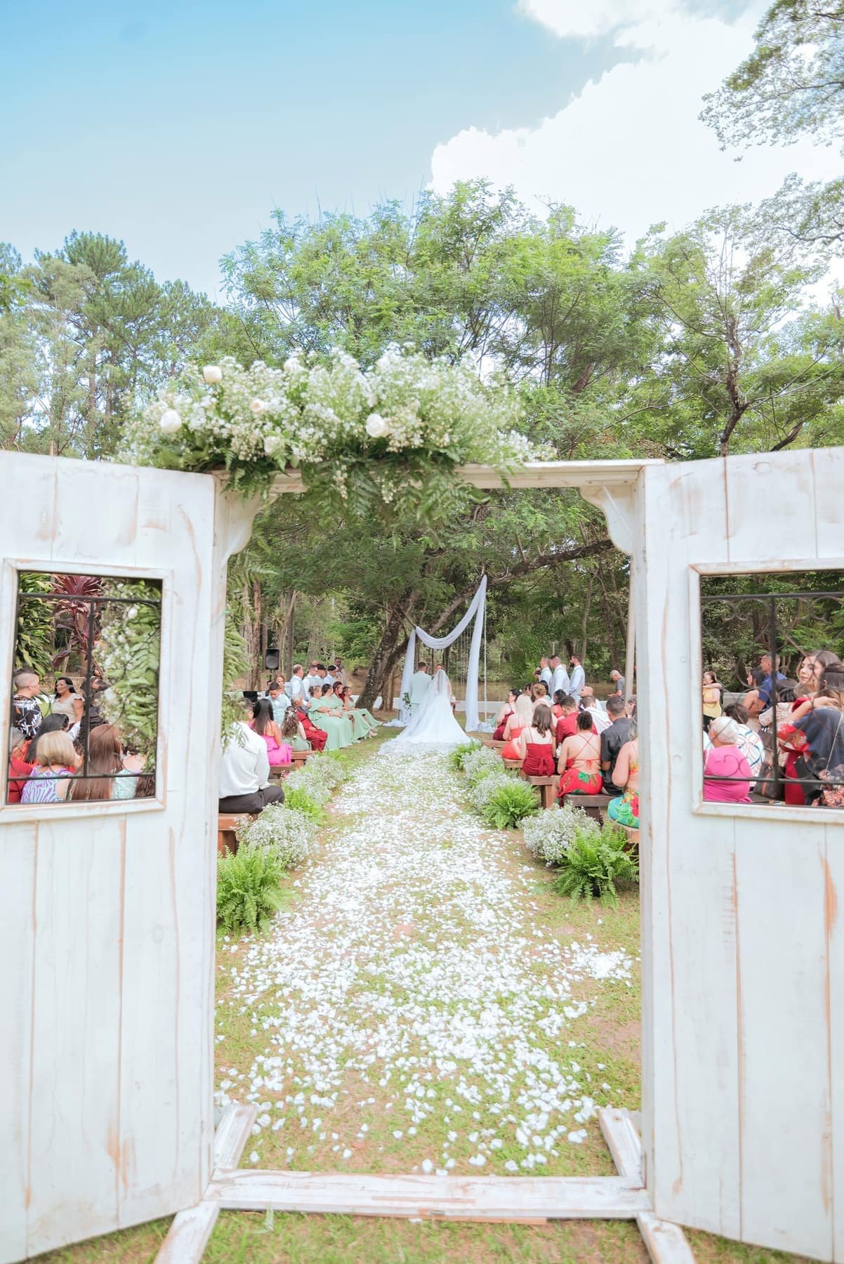 Entrada da cerimônia com portas rústicas e caminho de pétalas