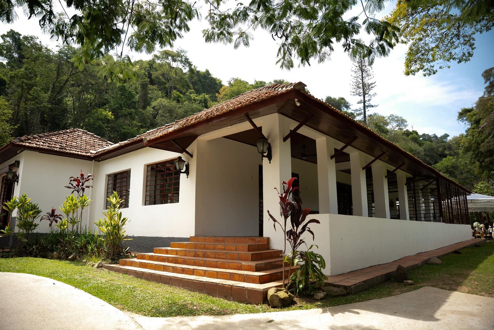 Fachada do casarão da Fazenda Moinho com jardim e luz natural