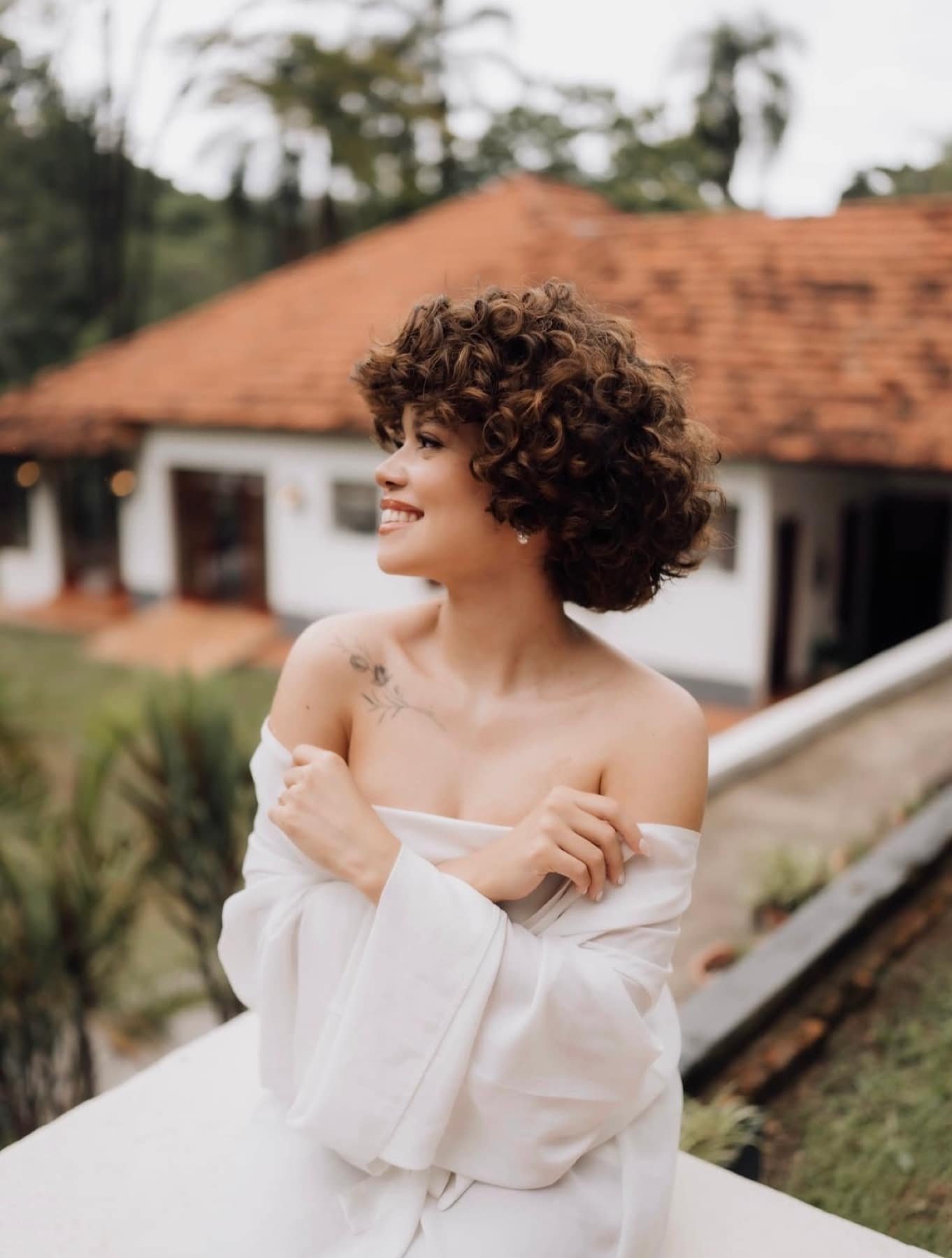 Noiva com robe diante do casarão