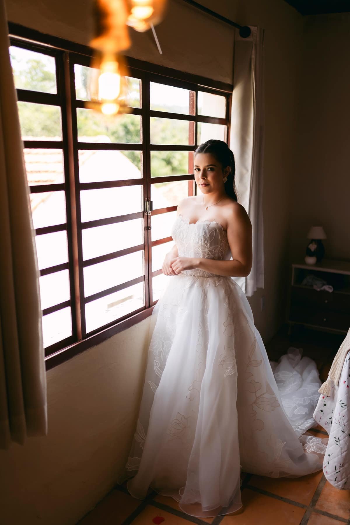 Noiva pronta em vestido de casamento junto à janela