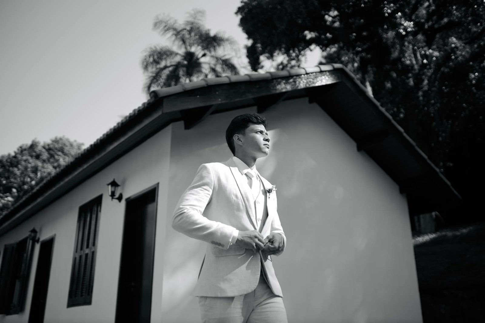 Noivo em retrato preto e branco junto ao casarão