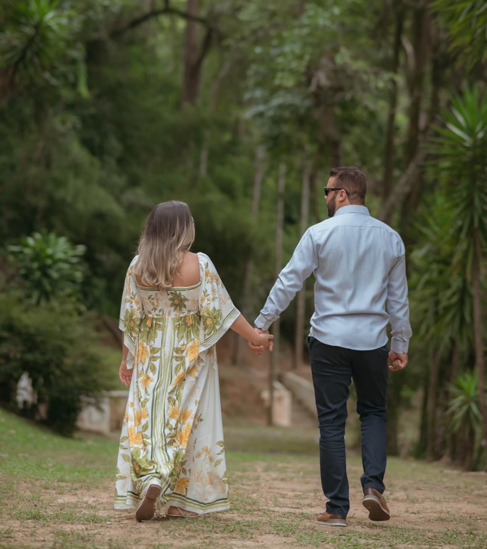 Casal de mãos dadas caminhando por caminho verde da Fazenda