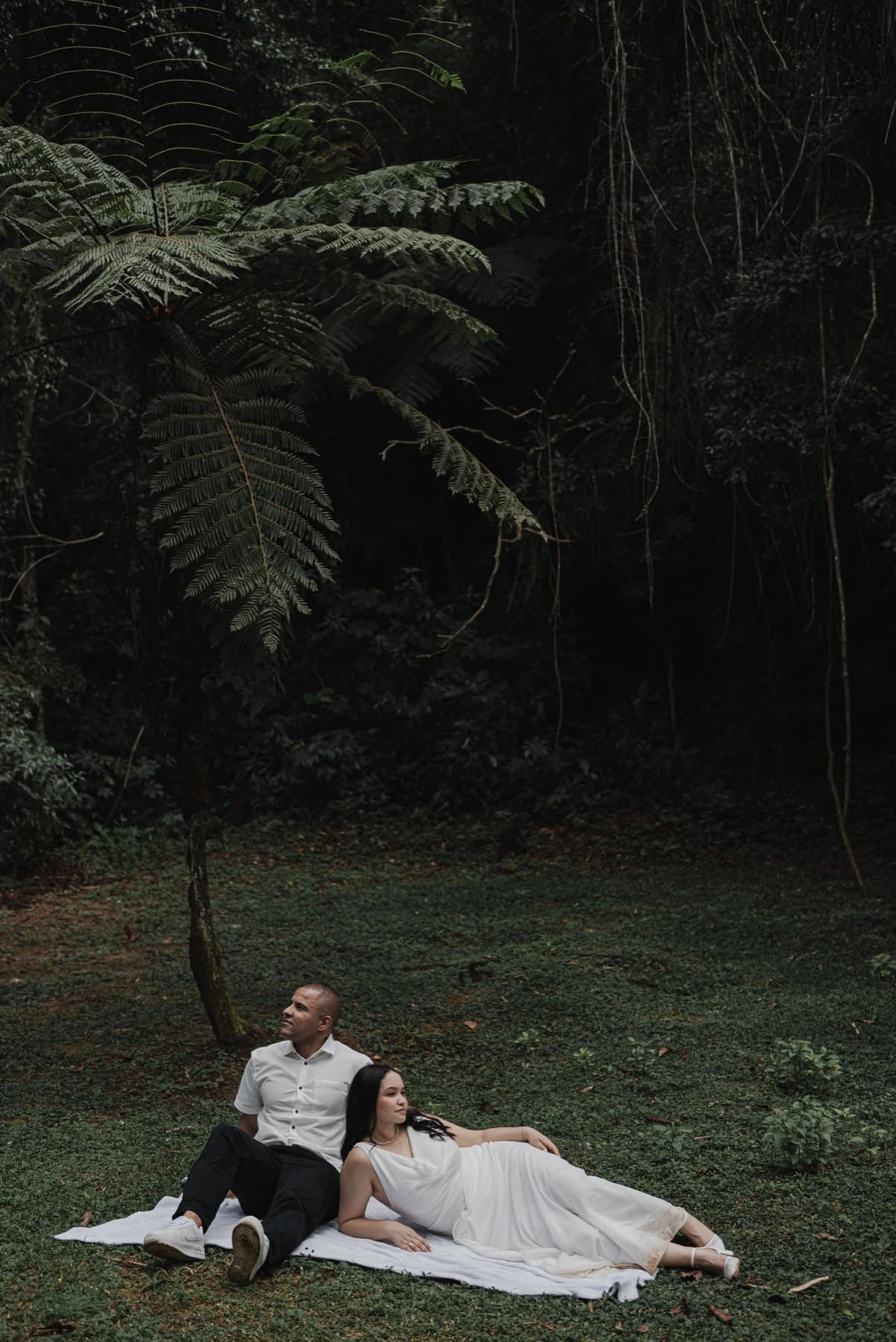 Casal sentado no bosque durante ensaio pré wedding