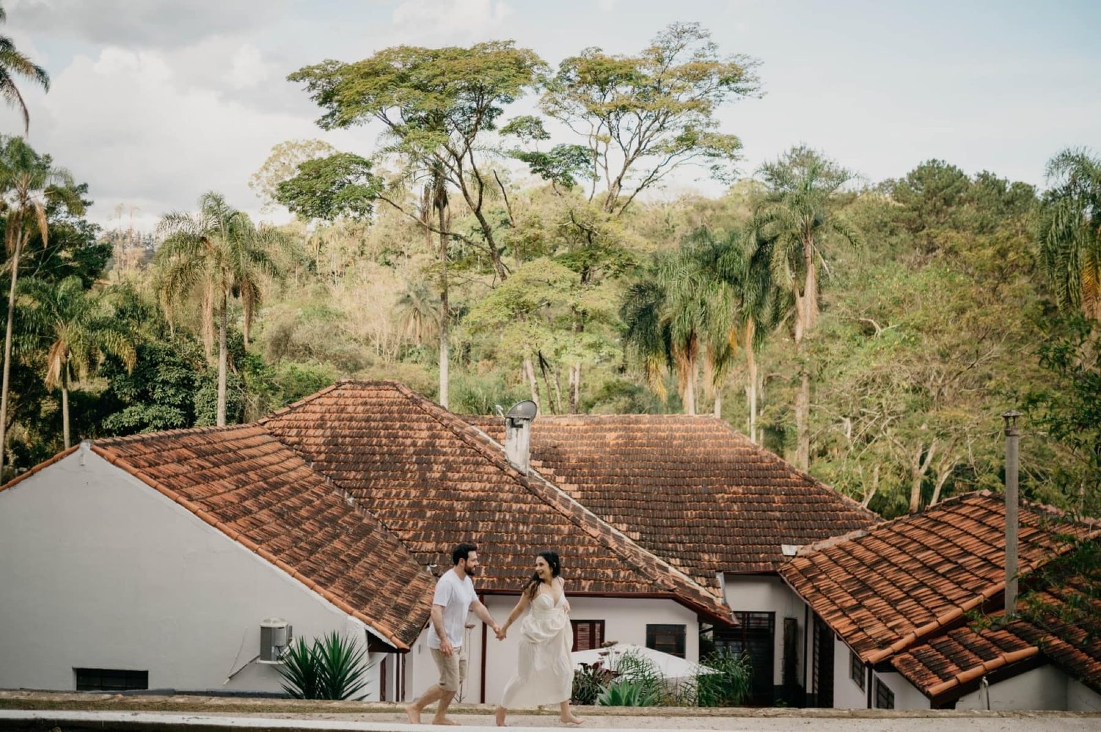 Casal caminhando com os telhados da Fazenda ao fundo