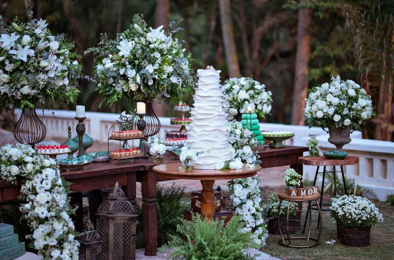 Mesa de bolo com flores brancas no jardim