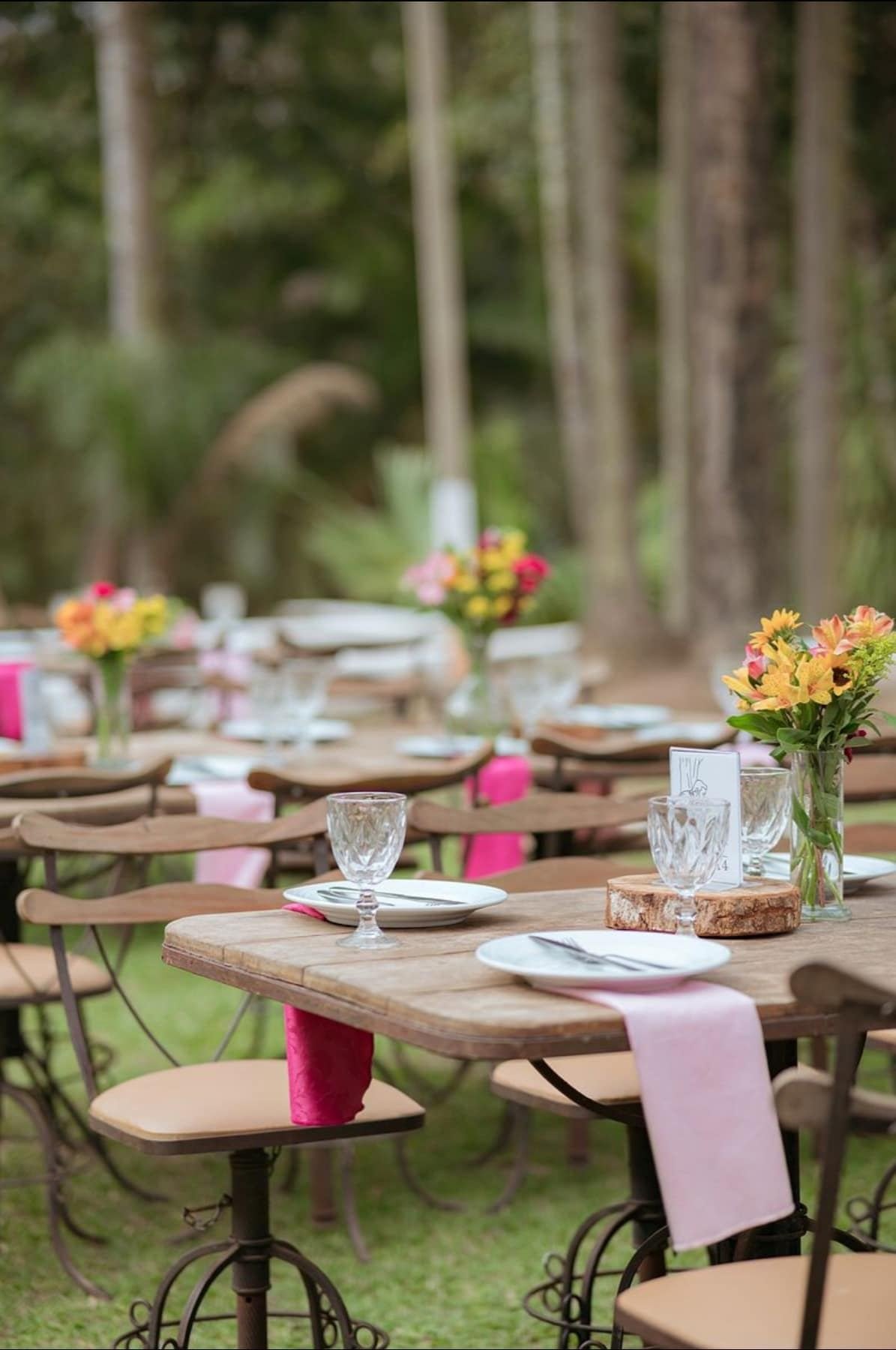 Mesa rústica de recepção com flores e guardanapos rosa