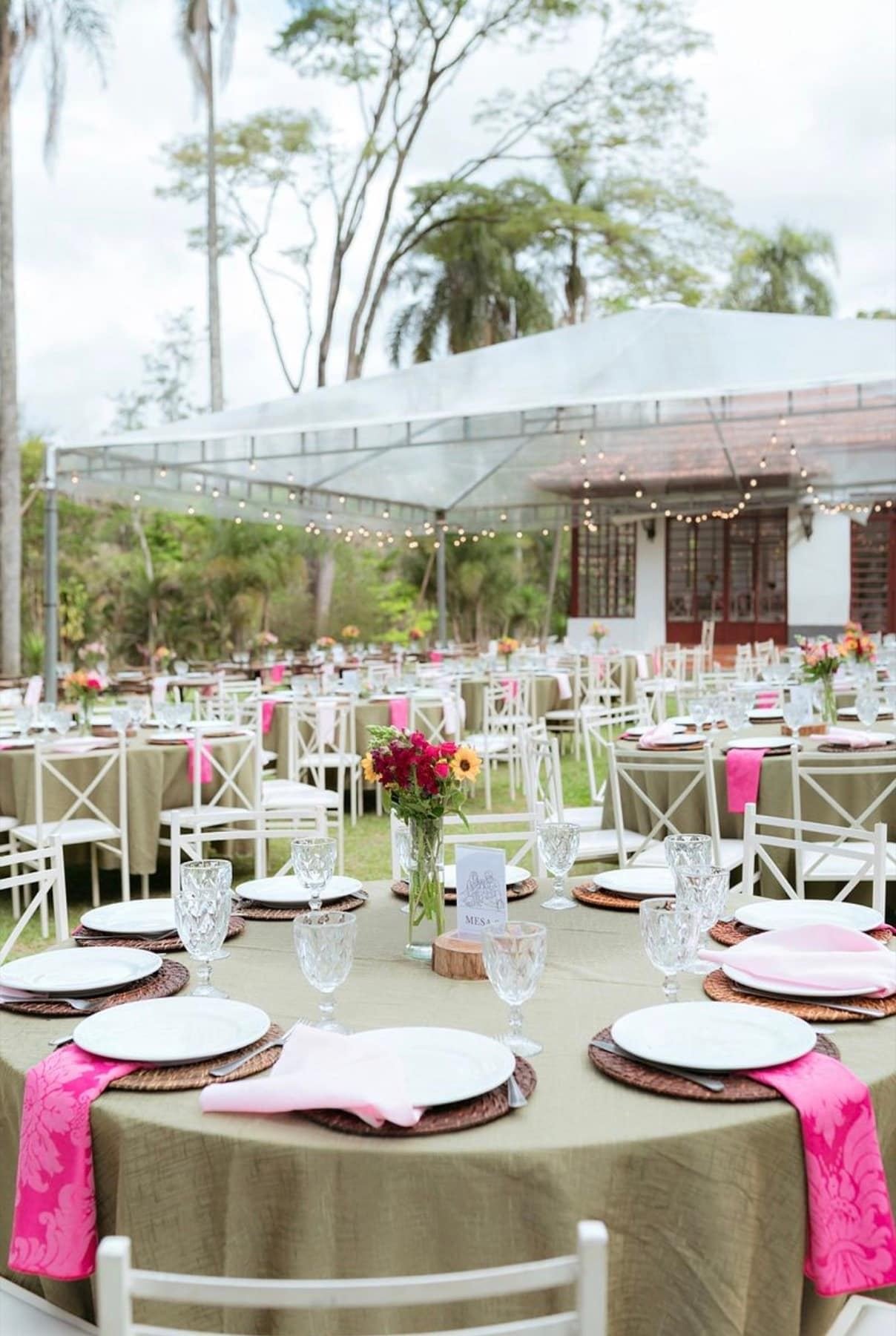 Recepção sob tenda com mesas e detalhes em rosa